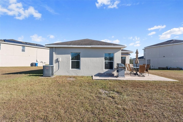 rear view of house with a lawn, central air condition unit, and a patio