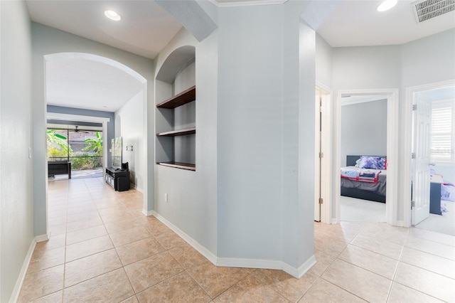 corridor featuring built in shelves and light tile patterned flooring