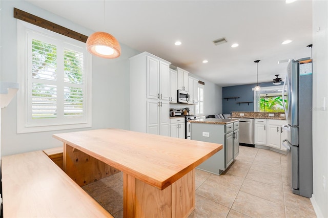 kitchen with a kitchen island, white cabinetry, hanging light fixtures, and appliances with stainless steel finishes