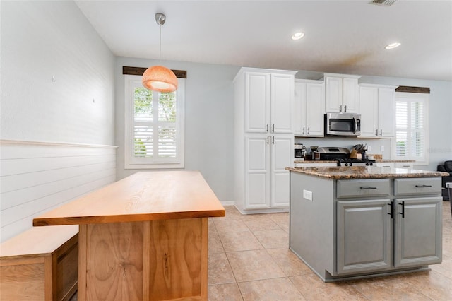 kitchen with white cabinets, plenty of natural light, a kitchen island, and stainless steel appliances