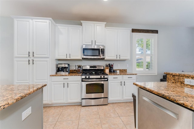 kitchen featuring light stone countertops, white cabinets, stainless steel appliances, and light tile patterned floors