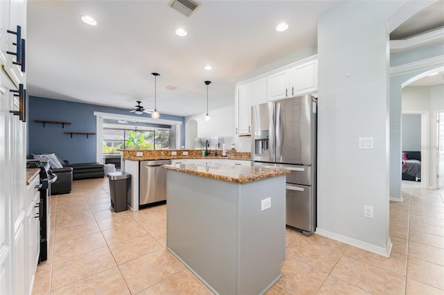 kitchen featuring kitchen peninsula, stainless steel appliances, a kitchen island, and hanging light fixtures