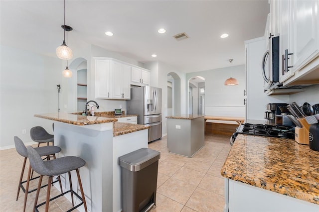 kitchen with kitchen peninsula, white cabinets, hanging light fixtures, and appliances with stainless steel finishes