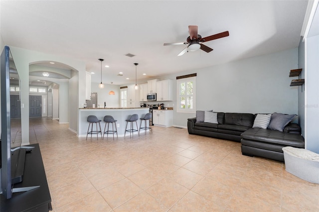 living room featuring ceiling fan, sink, and light tile patterned flooring