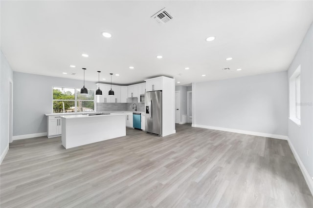 kitchen featuring pendant lighting, a center island, white cabinets, appliances with stainless steel finishes, and light hardwood / wood-style floors