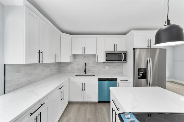 kitchen with white cabinetry, sink, stainless steel appliances, light hardwood / wood-style flooring, and pendant lighting