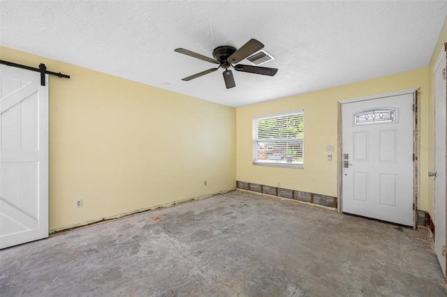 entryway with concrete flooring, a textured ceiling, a barn door, and ceiling fan