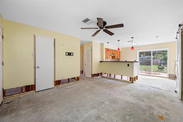 unfurnished living room with ceiling fan, sink, and a textured ceiling