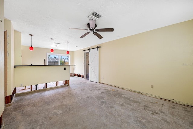 interior space featuring a barn door, ceiling fan, and concrete floors