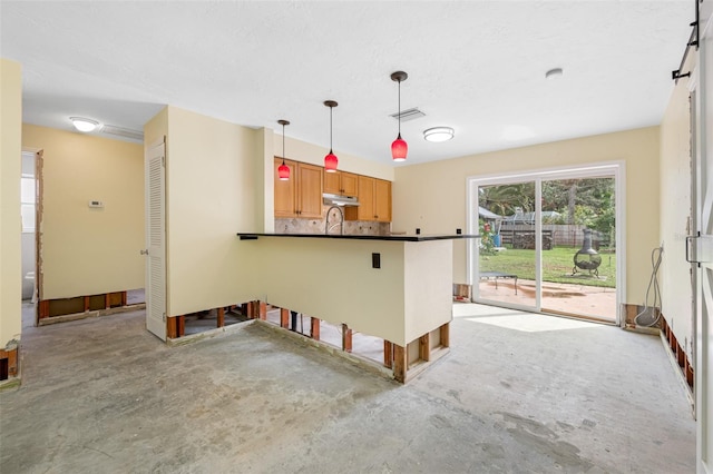 kitchen with kitchen peninsula, tasteful backsplash, hanging light fixtures, and sink