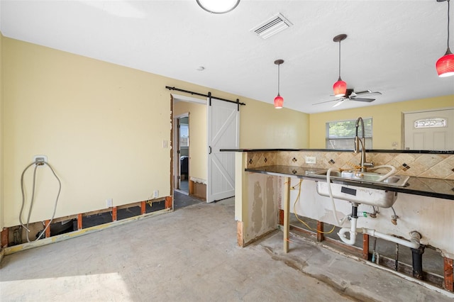 kitchen featuring a barn door, ceiling fan, concrete floors, and backsplash