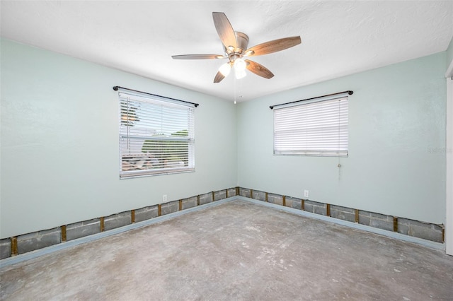 empty room with ceiling fan, concrete flooring, and a textured ceiling