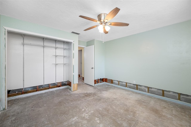 unfurnished bedroom featuring ceiling fan, concrete flooring, a textured ceiling, and a closet