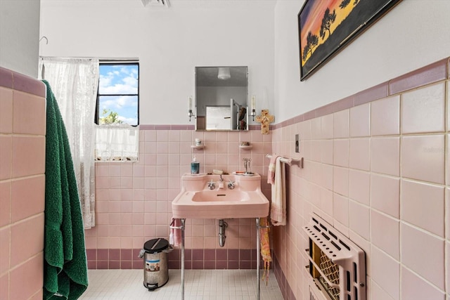 bathroom with tile patterned floors, heating unit, sink, and tile walls