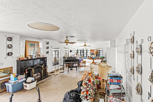 living room featuring hardwood / wood-style flooring, ceiling fan, a textured ceiling, and a tiled fireplace