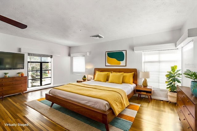 bedroom featuring ceiling fan, dark hardwood / wood-style flooring, and a textured ceiling