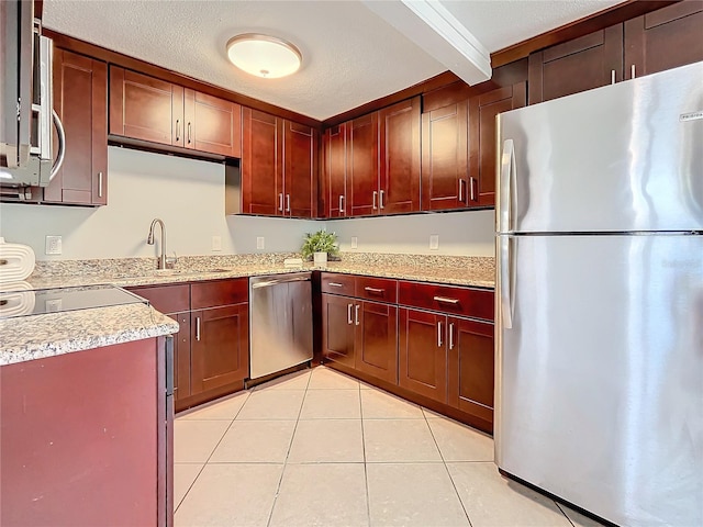 kitchen with sink, stainless steel appliances, beamed ceiling, a textured ceiling, and light tile patterned flooring