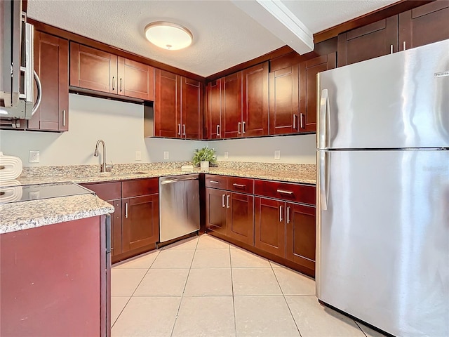 516 64th St S, Saint Petersburg, FL 33707 - kitchen with appliances with stainless steel finishes, reddish brown cabinets, light tile patterned floors, a sink, and light stone countertops