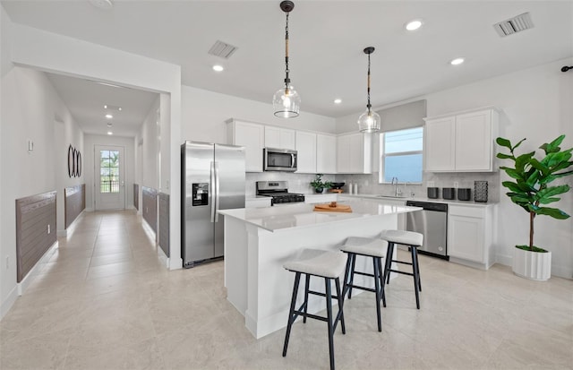 kitchen featuring a center island, a healthy amount of sunlight, white cabinets, and appliances with stainless steel finishes