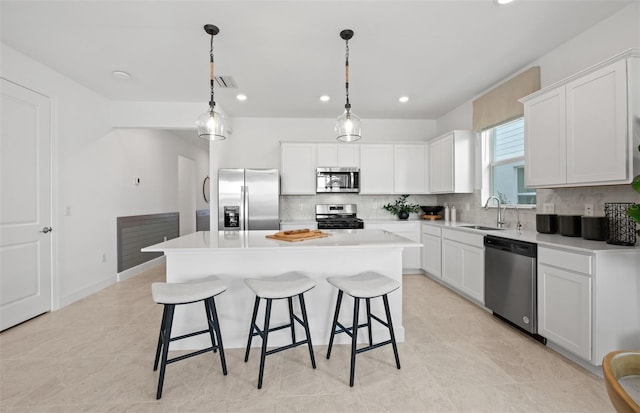 kitchen with a center island, white cabinets, stainless steel appliances, and decorative light fixtures