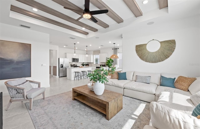 tiled living room with beamed ceiling and ceiling fan