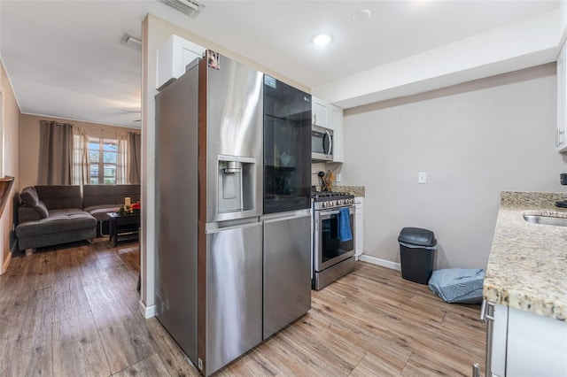 kitchen with sink, white cabinets, stainless steel appliances, and light wood-type flooring