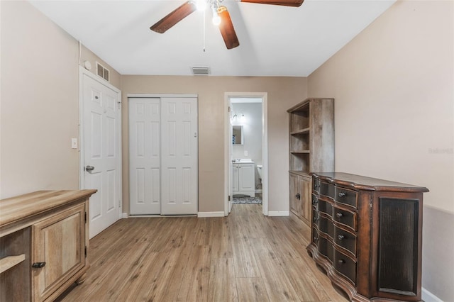 interior space with light wood-type flooring, a closet, ensuite bath, and ceiling fan