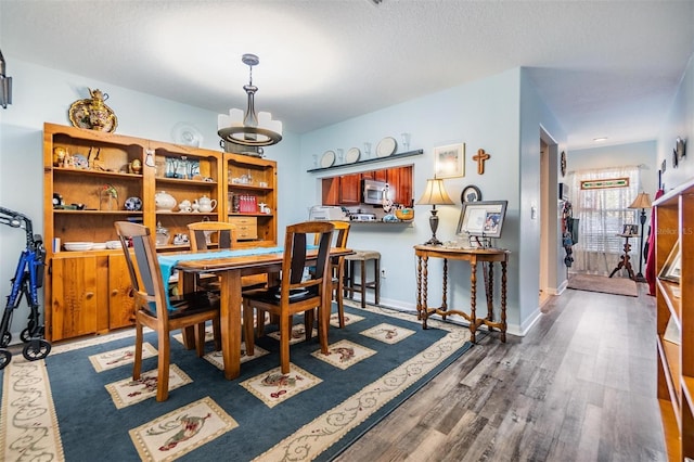 dining room with a textured ceiling and dark hardwood / wood-style flooring