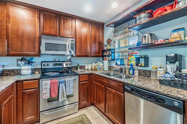 kitchen with light tile patterned floors, stainless steel appliances, sink, and dark stone countertops