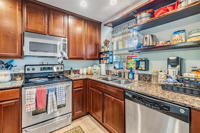 kitchen with stainless steel appliances, sink, light tile patterned floors, and light stone counters