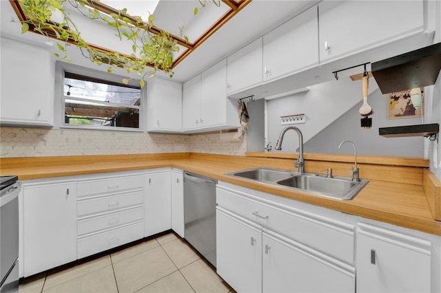 kitchen featuring white cabinets, appliances with stainless steel finishes, light tile patterned floors, and sink