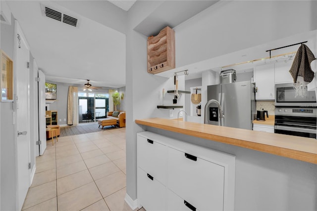 kitchen with ceiling fan, stainless steel appliances, tasteful backsplash, light tile patterned flooring, and white cabinets