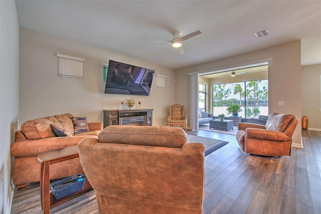 living room featuring ceiling fan, a textured ceiling, and hardwood / wood-style flooring