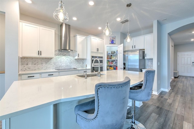 kitchen with white cabinetry, wall chimney range hood, a kitchen island with sink, and dark wood-type flooring