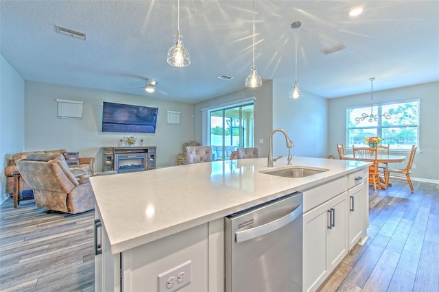 kitchen with stainless steel dishwasher, sink, a center island with sink, light hardwood / wood-style flooring, and white cabinets