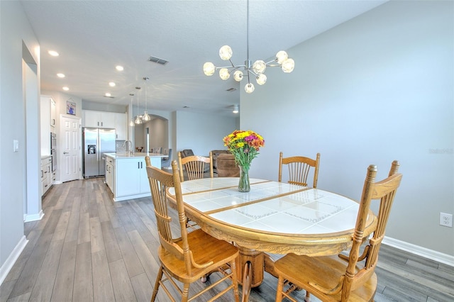 dining area featuring hardwood / wood-style floors, an inviting chandelier, and sink