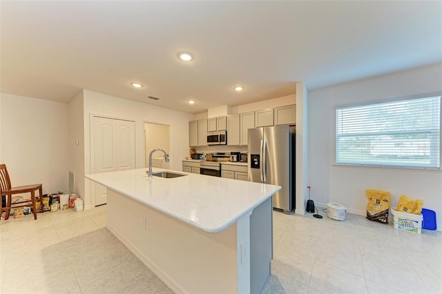 kitchen featuring gray cabinetry, stainless steel appliances, a kitchen island with sink, sink, and light tile patterned flooring