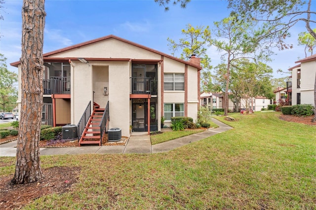 back of property with a yard and central AC unit