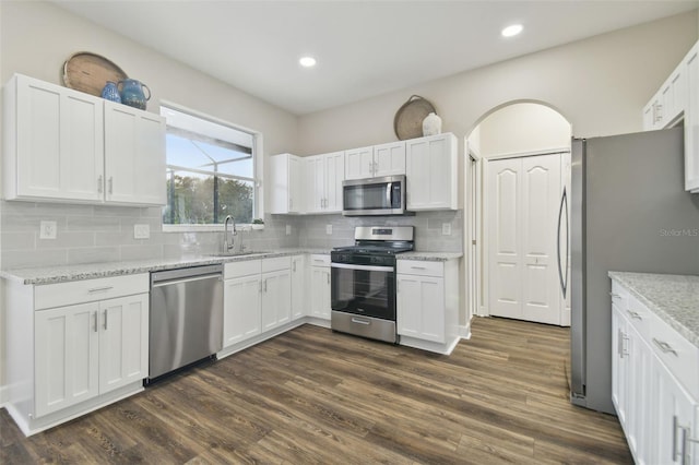 kitchen with decorative backsplash, dark hardwood / wood-style flooring, white cabinets, appliances with stainless steel finishes, and sink