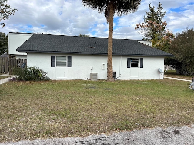 back of house featuring a lawn and central air condition unit