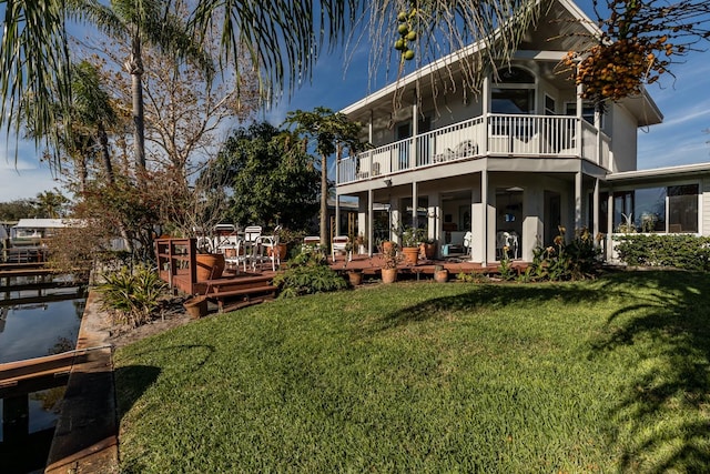 rear view of property featuring a lawn and a balcony