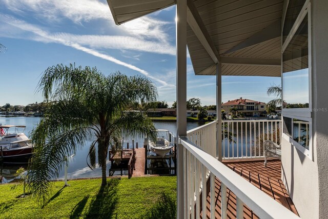 view of dock with a lawn and a water view