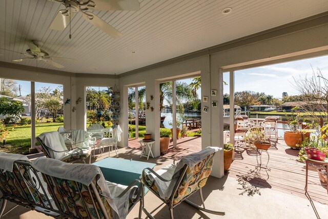 sunroom with ceiling fan and a water view