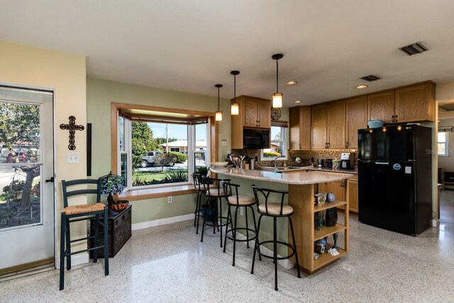 kitchen featuring kitchen peninsula, decorative backsplash, sink, black appliances, and decorative light fixtures