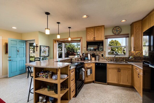 kitchen featuring sink, kitchen peninsula, pendant lighting, decorative backsplash, and black appliances