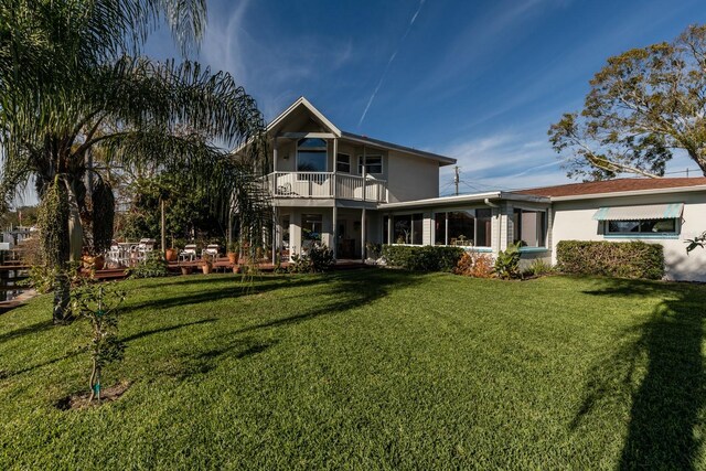 back of house with a balcony and a lawn