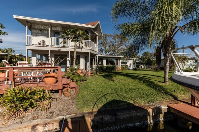 rear view of property with a balcony and a yard