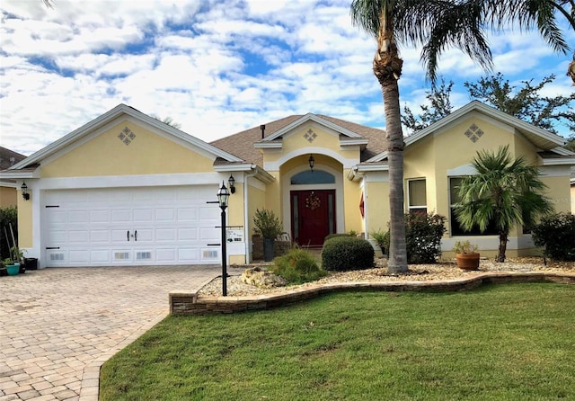 view of front of house featuring a garage, decorative driveway, a front lawn, and stucco siding