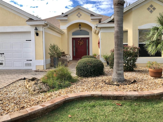 property entrance featuring a garage and stucco siding