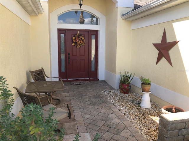 property entrance featuring a shingled roof and stucco siding